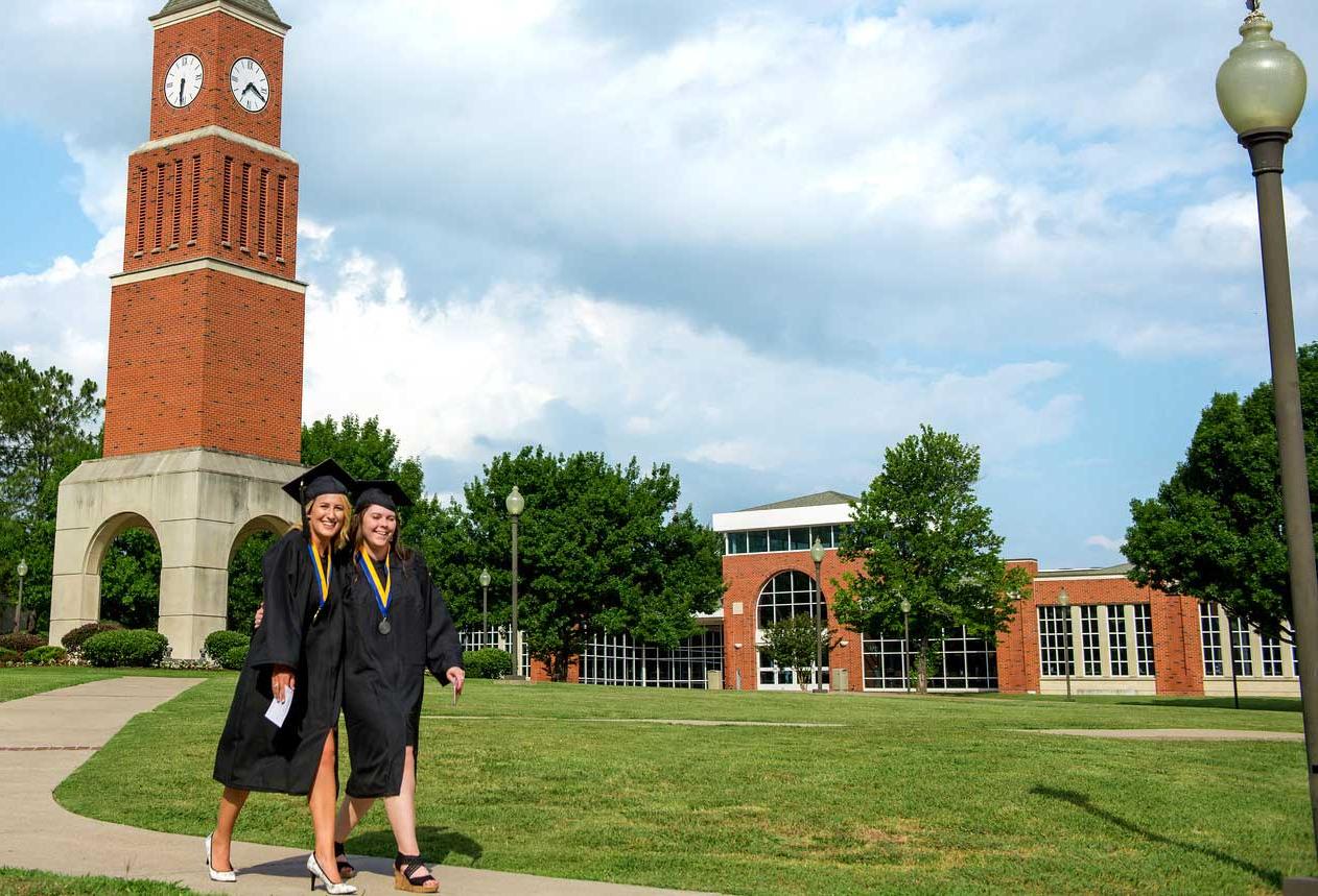 Two graduating females in front of the clock tower on the Navarro campus.